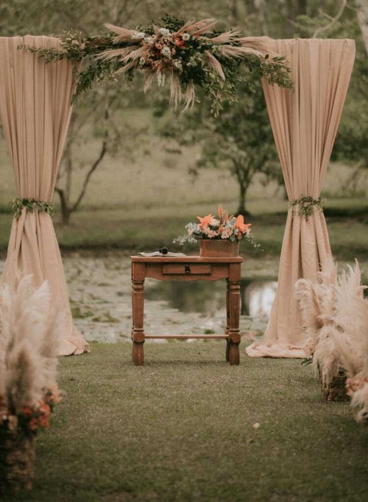 Beautiful rustic wedding altar setup by a pond with natural decorations.